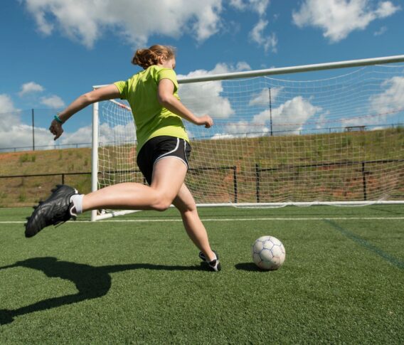 girl playing soccer on athletic field